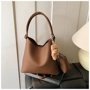 Détail du sac seau en cuir grainé marron avec breloque ours en peluche et petite pochette