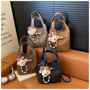 Détail de sacs seaux en cuir grainé avec pendentifs ours en perles en quatre couleurs