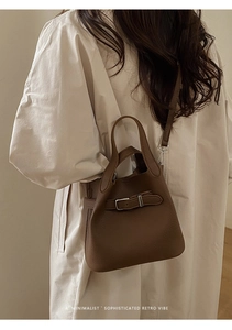Brown litchi grain leather bucket bag shown as a crossbody on a model with retro vibe