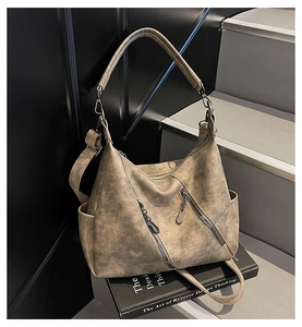 Détail du sac bandoulière marron vintage avec texture cuir mat et poche latérale sur marches