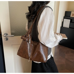 Detail of vintage dark brown faux leather hobo bag with a side decorative charm pouch