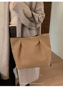 Detailed side view of khaki minimalist tote bag showing pleat texture and metal button