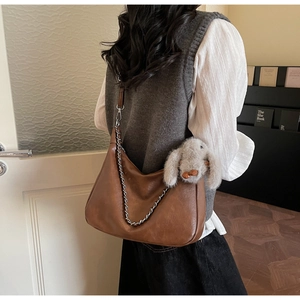 Detailed close-up of brown vintage hobo bag with silver chain and cute rabbit plush charm