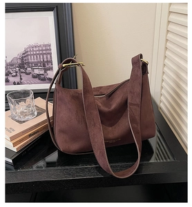 Detailaufnahme der tiefbraunen Wildleder-Hobo-Tasche mit goldener Schnalle und Prägung