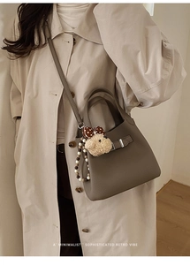 Chic grey pebbled leather bucket bag with cute bear charm worn with beige trench coat