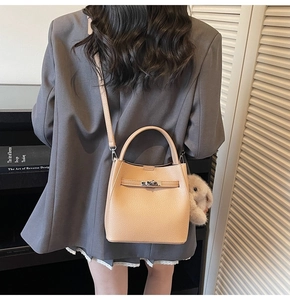 Détail du sac seau en cuir abricot avec un adorable lapin en peluche sur le côté
