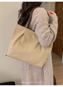 Detail of minimalist beige tote bag with metallic rivet and retro style worn with sweater