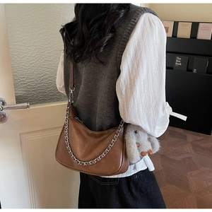 Close-up of brown leather crescent underarm bag with silver chain and bunny charm