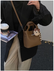 Détail du sac seau marron à motif litchi avec breloque ours et fermoir argenté