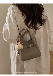 Chic dark brown lychee leather bucket bag with a cute teddy bear charm on beige shirt