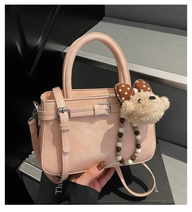 Détail du sac à main rose avec pendentif ours en peluche et boucles métalliques élégantes