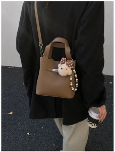 Détail du sac en cuir marron foncé avec fermoir métallique et breloque ours mignon