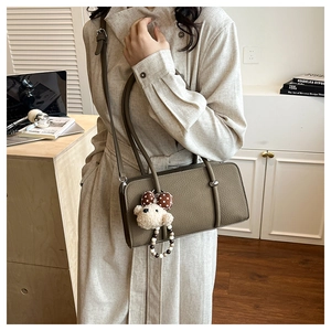 Detail view of lychee pattern leather shoulder bag with a cute plush bear charm accessory