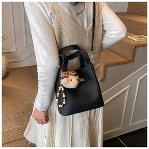 Détail du sac seau noir en cuir grainé avec un charm d'ours mignon et des perles