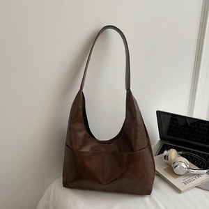 Detail view of large dark brown hobo bag with side pockets in a professional office setting