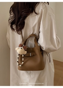 Detail of brown litchi pattern leather bucket bag with a cute plush bear charm