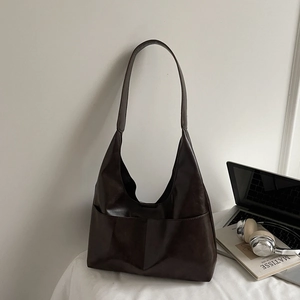 Detailed view of dark brown faux suede tote bag with front pockets on a minimalist desk