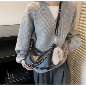 Detail of black crescent shoulder bag with silver chain and white plush rabbit charm