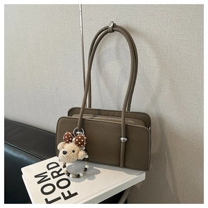 Detail of coffee brown pebble leather bag with silver zipper and cute bear charm accessory