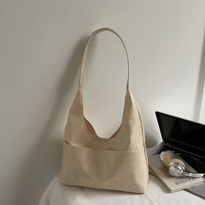 Detail of minimalist beige suede hobo bag with large front pocket and soft shoulder strap