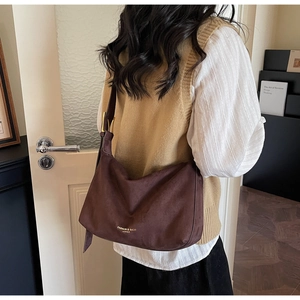 Detailansicht der matt dunkelbraunen Hobo-Tasche mit goldenem Schriftzug und Schnallenriemen