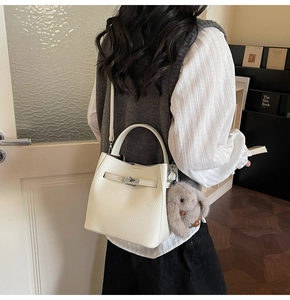 Détail d'un sac seau en cuir crème avec fermoir rotatif et breloque lapin en peluche doux
