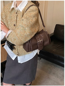Detail of dark brown vintage baguette bag with wide metal buckle worn by model