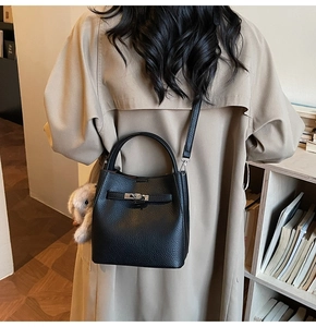 Détail du sac seau noir en cuir grainé avec fermoir argenté et breloque lapin en peluche