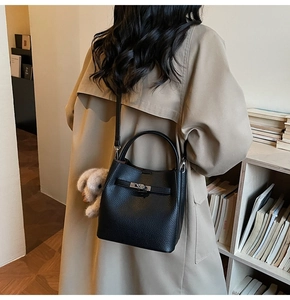 Sac seau en cuir grainé avec fermoir argenté et breloque lapin dans une scène de librairie