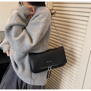 Close-up of black lychee grain leather crossbody bag with chain strap and tassels