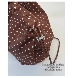 Dettaglio borsa in tela a pois con chiusura a coulisse e tracolla regolabile