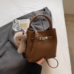 Détail du sac seau en cuir grainé marron avec fermoir argenté et charm lapin en peluche