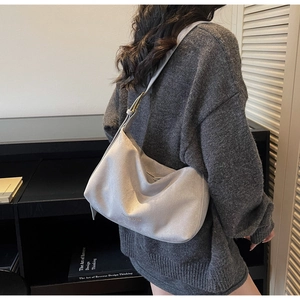 Detailansicht der hellgrauen Hobo-Tasche aus Wildleder mit Riemen und geprägtem Logo