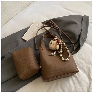 Détail d'un sac seau en cuir litchi marron avec fermoir et breloque ourson doux
