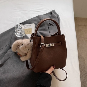 Détail du sac seau en cuir grainé marron chocolat avec un fermoir rotatif en métal argenté
