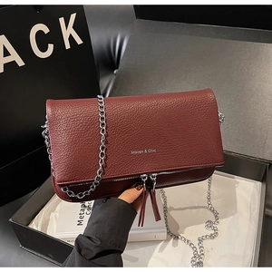 Detail of burgundy lychee leather shoulder bag with silver chain and double zipper