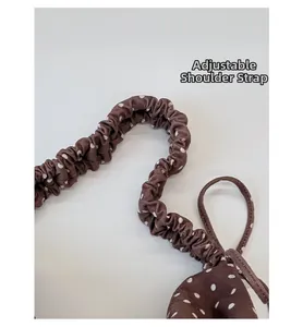 Dettaglio della tracolla regolabile su borsa a pois marrone con design a volant