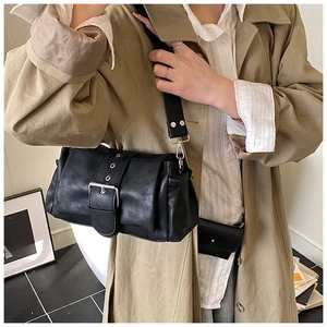 Close-up of black retro shoulder bag with large metal buckle and matte leather texture