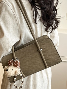 Chic olive green leitchi grain leather baguette bag with a cute teddy bear charm