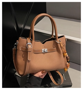 Détail du sac vintage en toile marron avec bordure en cuir et breloque en perles de bois