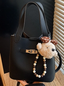Sac seau classique en cuir noir avec breloque ours mignon sur un bureau en bois