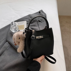 Détail du sac seau en cuir litchi noir avec fermoir rotatif argenté et charm lapin doux