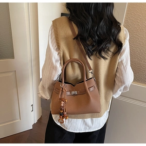 Détail du sac à main en cuir marron à motif litchi avec boucle et pompon en bois