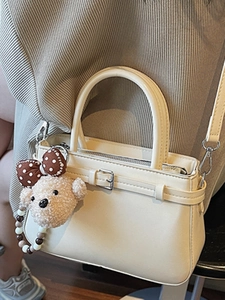 Sac à main beige minimaliste avec charm ours et bandoulière perlée en décor intérieur