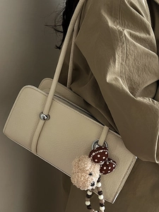 Chic beige faux leather baguette bag with textured grain and cute teddy bear charm