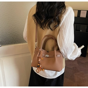 Sac à main marron en simili cuir avec fermoir rotatif argenté et pompon ethnique