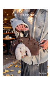 Detail of vintage brown leather handbag featuring a cute plush rabbit charm accessory