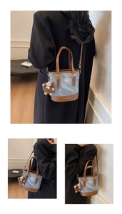 Close-up of denim bucket bag with leather base, handles and cute plush charm pendant