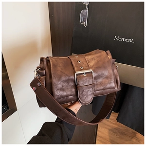 Detail of vintage brown leather handbag featuring textured grain and metallic buckle