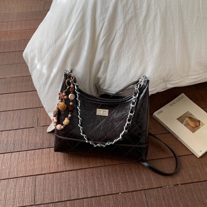 Détail d'un sac bandoulière marron matelassé avec chaîne argentée et perles décoratives